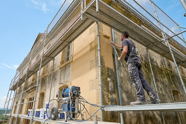 Artisan peintre réalisant un ravalement de façade sur échafaudage